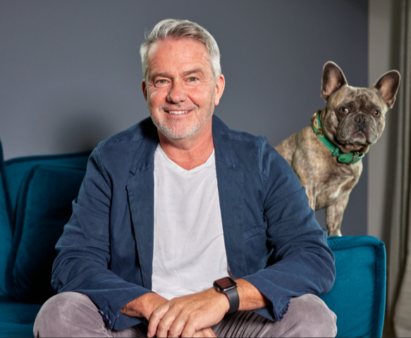 Thomas Scheuer auf blauem Sofa mit seinem Hund
